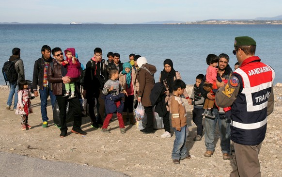 A Turkish Gendarme leads a group of refugees to buses to prevent them from sailing off for the Greek island of Chios by dinghies, at a beach in the western Turkish coastal town of Cesme, in Izmir prov ...