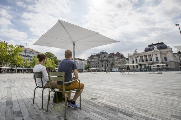 Zwei Passanten sitzen im Schatten der neuen Sonnenschirme von der Stadt Zuerich auf dem Sechselaeutenplatz am Freitag 4. August 2017 in Zuerich. (KEYSTONE/Christian Merz)