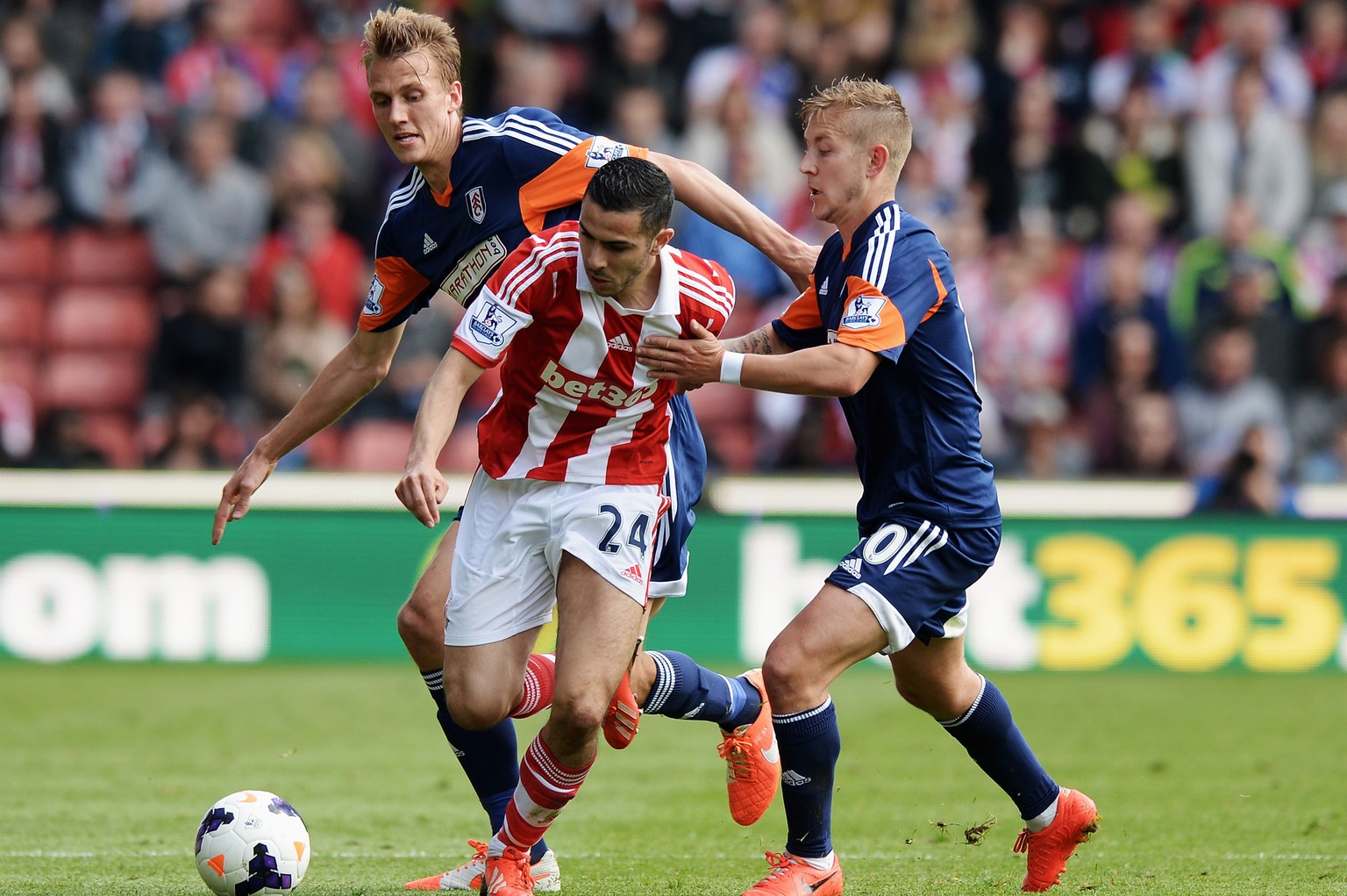 STOKE ON TRENT, ENGLAND - MAY 03: Oussama Assaidi (C) of Stoke City is challenged by Dan Burn (L) and Lewis Holtby (R) of Fulham during the Barclays Premier League match between Stoke City and Fulham  ...