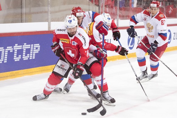 SwitzerlandÕs Denis Hollenstein, left, Russia&#039;s Igor Ozhiganov, center, and SwitzerlandÕs Vincent Praplan, right, in action during a friendly ice hockey game between Switzerland and Russia, at th ...