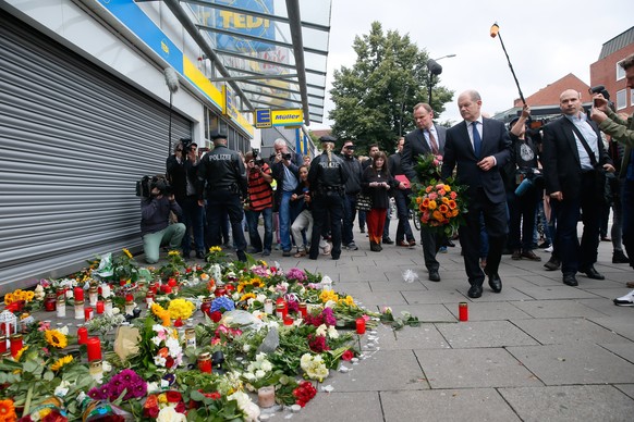 Blumen legt Hamburgs Erster Bürgermeister Olaf Scholz (SPD) neben Innensenator Andy Grote am 29.07.2017 in Hamburg-Barmbek vor dem Supermarkt ab, in dem am 28.07.2017 ein Mann einen Menschen mit einem ...