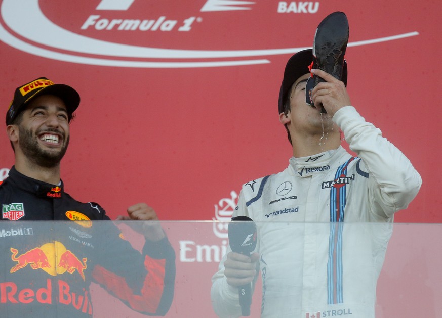 Williams driver Lance Stroll of Canada takes a celebratory drink from the boot of Red Bull driver Daniel Ricciardo of Australia, left, who is winner the Formula One Azerbaijan Grand Prix in Baku, Azer ...