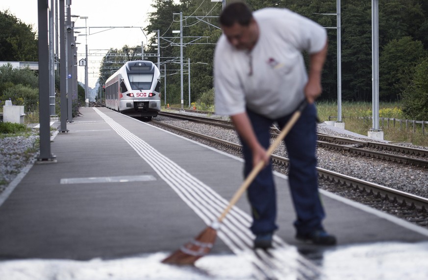 epa05480996 A man cleans the platform as the train stands at the station following an attack onboard, in Salez, Switzerland, 13 August 2016. According to St. Gallen Canton Police Department, a 27 year ...