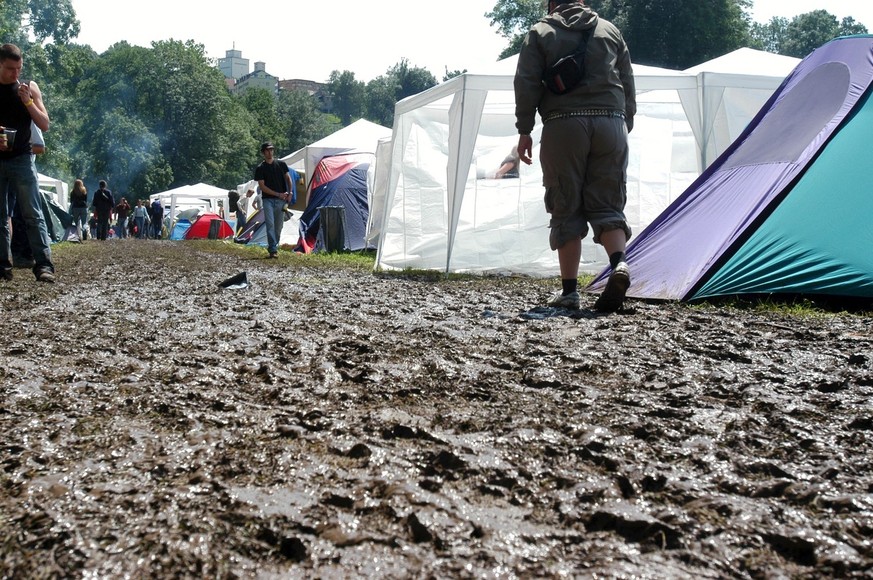 Ein Besucher des Open Air St. Gallen geht auf dem schlammigen Weg durch den Zeltplatz, am Freitag 2. Juli 2004, am 28. Open Air St. Gallen im Sittertobel. Das Open Air St. Gallen zieht jedes Jahr Zehn ...