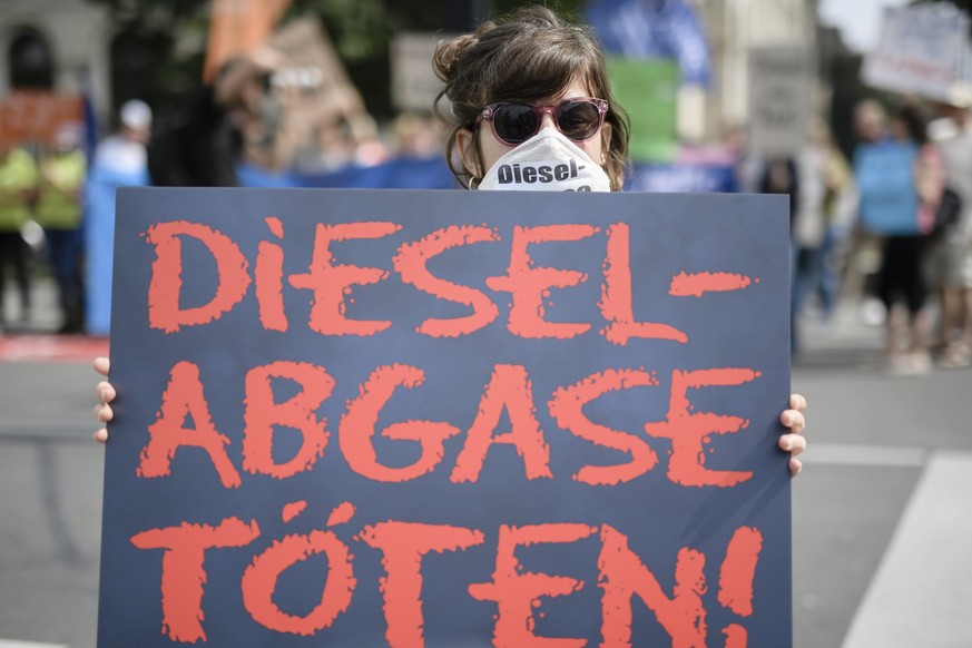 epa06120951 A protestor wears a mask and a cardboard reading &#039;Diesel-Abgase toeten! (Diesel emission kills), in front of the Ministry of Transport, in Berlin, Germany, 02 August 2017. Representat ...