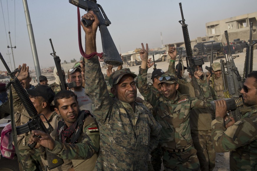 Iraqi army soldiers raise their weapons in celebration on the outskirts of Qayyarah, Iraq, Wednesday, Oct. 19, 2016. A senior Iraqi general on Wednesday called on Iraqis fighting for the Islamic State ...