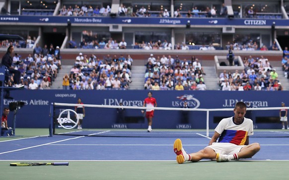 Mikhail Youzhny, of Russia, sits on the court with a cramp in his leg after chasing down a shot from Roger Federer, of Switzerland, during the second round of the U.S. Open tennis tournament, Thursday ...