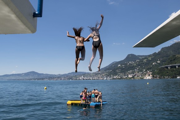 epa05416959 Young people jump from a diving platform into the Geneva Lake and enjoy sunny and warm weather, in Villeneuve, south western Switzerland, 09 July 2016. EPA/JEAN-CHRISTOPHE BOTT
