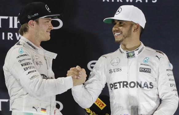 Mercedes driver Nico Rosberg of Germany, left, cheers his teammate Mercedes driver Lewis Hamilton of Britain on the podium after the Emirates Formula One Grand Prix at the Yas Marina racetrack in Abu  ...