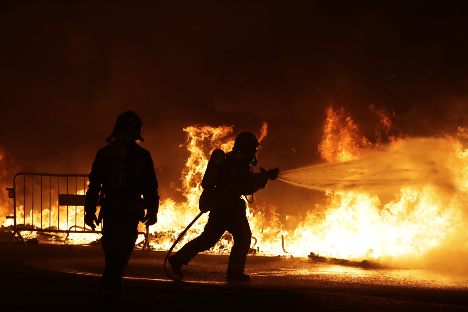 Firefighters try to put out burning barricades on the fifth day of protests over the conviction of a dozen Catalan independence leaders in Barcelona, Spain, Friday, Oct. 18, 2019. Tens of thousands of ...