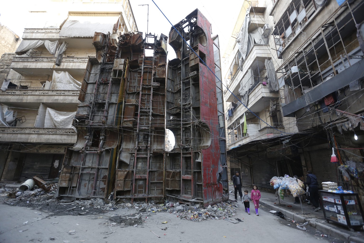 epaselect epa05767560 Children pass next to three damaged buses placed vertically, used as a barricade at a checkpoint during the conflicts, in the Bustan Alqasr neighborhood, one of the eastern neigh ...