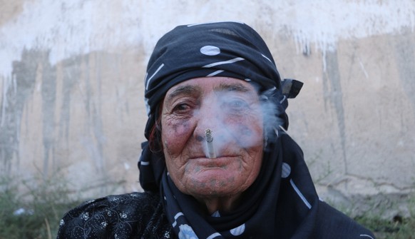 A woman smokes as she rests after she was evacuated with others by the Syria Democratic Forces (SDF) fighters from an Islamic State-controlled neighbourhood of Manbij, in Aleppo Governorate, Syria, Au ...
