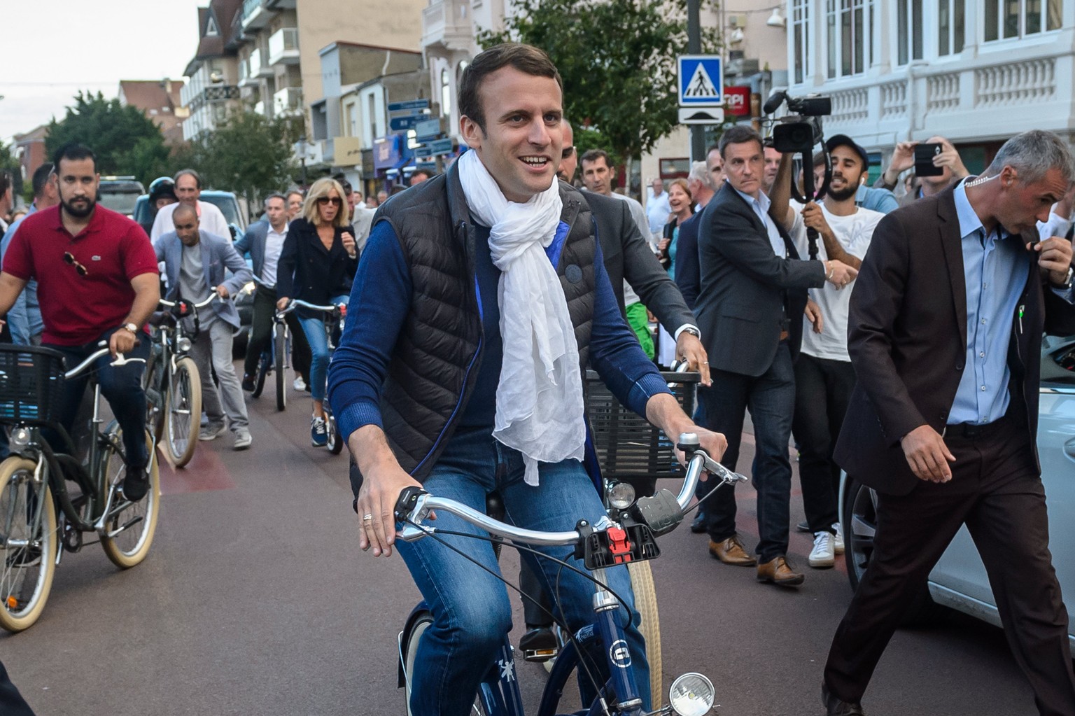 epa06021873 French President Emmanuel Macron (C) and his wife Brigitte Trogneux (L) leave home on bicycles the day before the first round of the French legislatives elections in Le Touquet, France, 10 ...