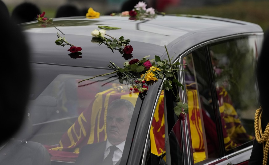 Flowers cover the hearse carrying the coffin of Queen Elizabeth II as it arrives outside Windsor Castle in Windsor, England, Monday, Sept. 19, 2022. The Queen, who died aged 96 on Sept. 8, will be bur ...