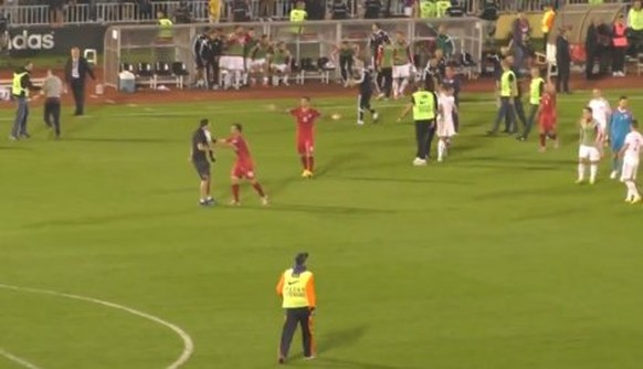 Lazovic und Kolarov (Bildmitte in Rot) halten einen Fan auf dem Spielfeld auf.