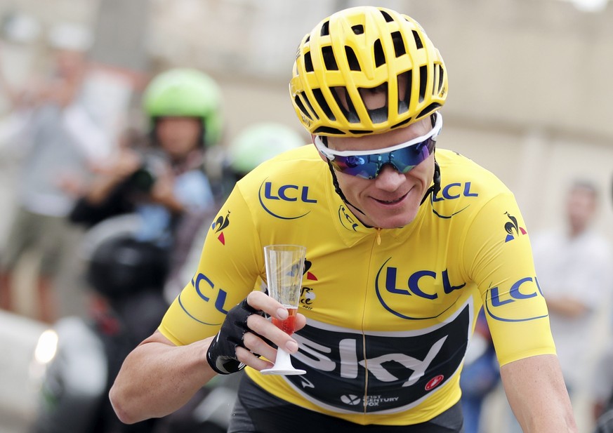 Britain&#039;s Chris Froome, wearing the overall leader&#039;s yellow jersey holds a glass during the twenty-first and last stage of the Tour de France cycling race over 103 kilometers (64 miles) with ...