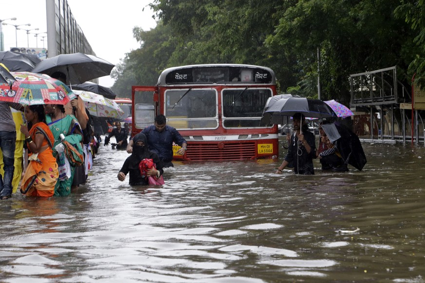 People walk through a waterlogged street following heavy rains in Mumbai, India, Tuesday, Aug. 29, 2017. Heavy rains Tuesday brought Mumbai to a halt flooding vast areas of the city. (AP Photo/Rajanis ...