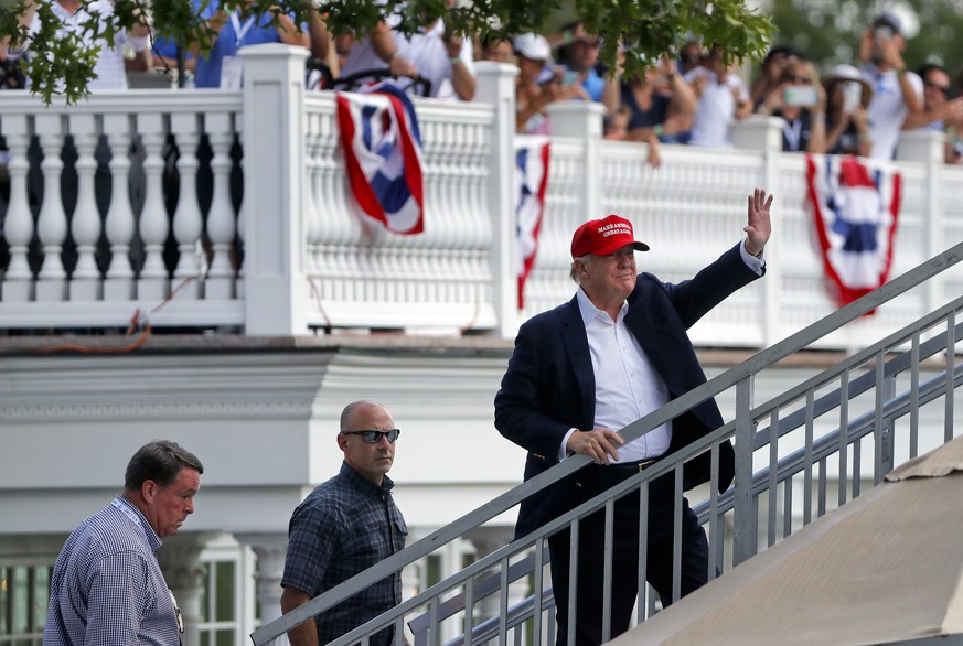 President Donald Trump waves to spectators as he walks up to his viewing booth on the 15th green at the Trump National Golf Club during the third round of the U.S. Women&#039;s Open Golf tournament Sa ...