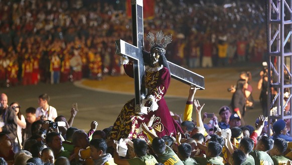 Roman Catholic devotees mount the image of the Black Nazarene on a hearse prior to a raucous procession to celebrate its feast day Tuesday, Jan. 9, 2018, in Manila, Philippines. A massive crowd of mos ...