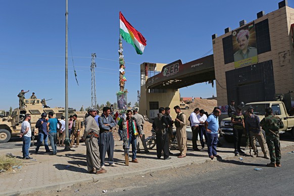 A picture of Massoud Barzani, the President of Iraq&#039;s autonomous Kurdish region, and a Kurdish flag are displayed as Kurdish security forces stand guard in Altun Kupri, on the outskirts of Irbil, ...