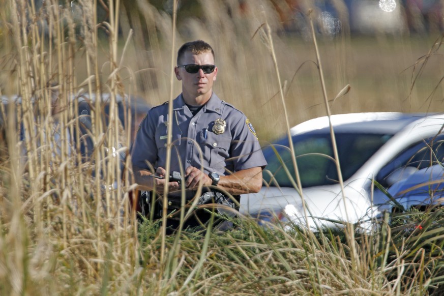 An Oklahoma City police officer looks through tall grass at a checkpoint at Will Rogers World Airport, Tuesday, Nov. 15 2016, in Oklahoma City. The airport was put on lockdown after a shooting at the  ...