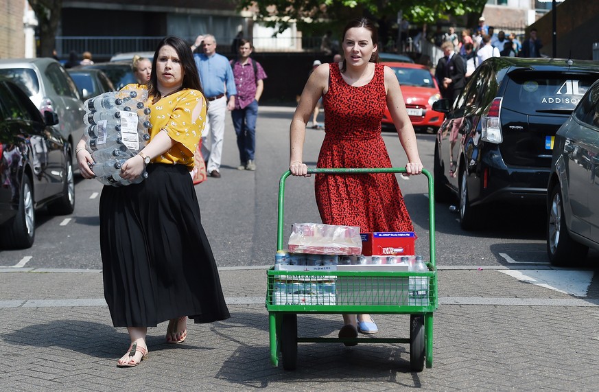 epa06027490 Volunteers bring food and water to local residents following a huge fire at the Grenfell Tower, a 24-storey apartment block in North Kensington, London, Britain, 14 June 2017. According to ...