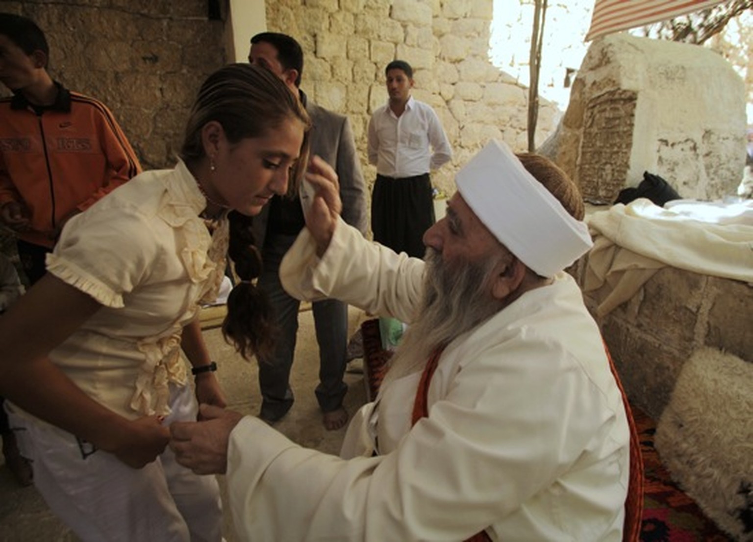 Ein Priester segnet eine Frau.