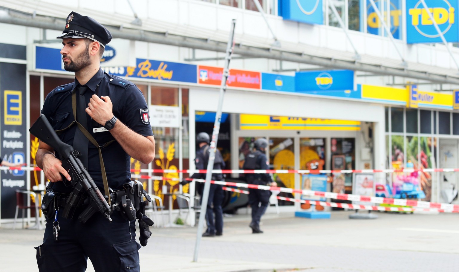 epa06114870 Police officers stands in front of a supermarket in Hamburg, Germany, 27 July 2017. According to police reports a man attacked several people in a supermarket in Hamburg. One victim is rep ...