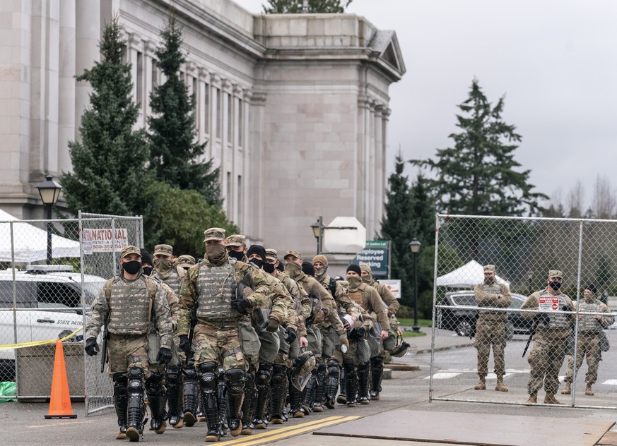 epa08944936 Members of the National Guard leave the perimeter of the Washington State Capitol while providing extra security in Olympia, Washington, USA, 17 January 2021. State capitols throughout the ...