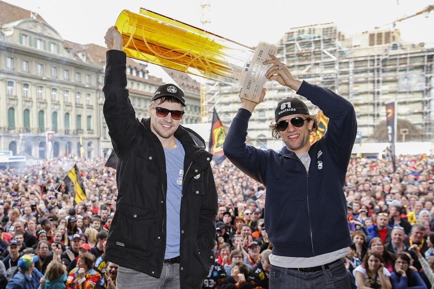 Die SCB Spieler Thomas Ruefenacht, rechts, und Luca Hischier halten den Meisterpokal hoch, bei der Meisterfeier des SCB am Samstag, 16. April 2016 auf dem Bundesplatz in Bern. (KEYSTONE/Peter Klaunzer ...