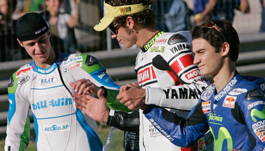 Newly crowned 125cc World Champion, Swiss motorcycle pilot Thomas Luethi, left, MotoGP World Champion Valentino Rossi from Italy, center, and 250cc World Champion Daniel Pedrosa from Italy hold hands  ...