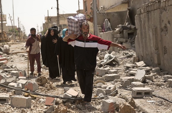 In this May 15, 2017, photo, Iraqi civilians walk through rubble as they flee fighting between Iraqi special forces and Islamic State militants, in western Mosul, Iraq. The United States is looking ah ...