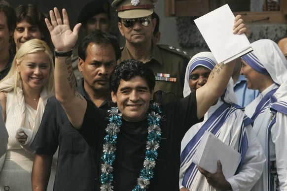 Argentina&#039;s soccer coach Diego Maradona, center, waves to the crowd as his girlfriend Veronica, left, sisters of Missionaries of Charity, right in white sarees, and security guards look on in Cal ...