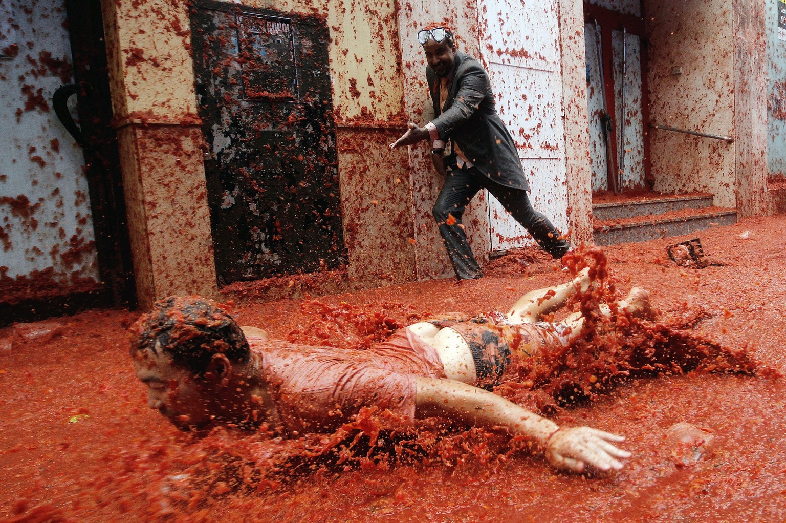 epa06171489 A man slides on the pavement covered with squashed tomatoes as he takes part in the traditional tomato fight called &#039;Tomatina&#039; in Bunol, Spain, 30 August 2017. As every year on t ...