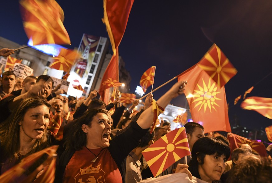 epa05862129 Supporters of the Civil Initiative for United Macedonia hold placards and flags as they shout slogans during a protest while European Commissioner for enlargement and Negotiations Johannes ...