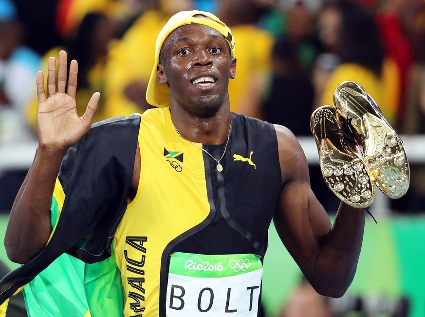 epa05486015 Usain Bolt of Jamaica carries his shoes after winning the men&#039;s 100m final of the Rio 2016 Olympic Games Athletics, Track and Field events at the Olympic Stadium in Rio de Janeiro, Br ...