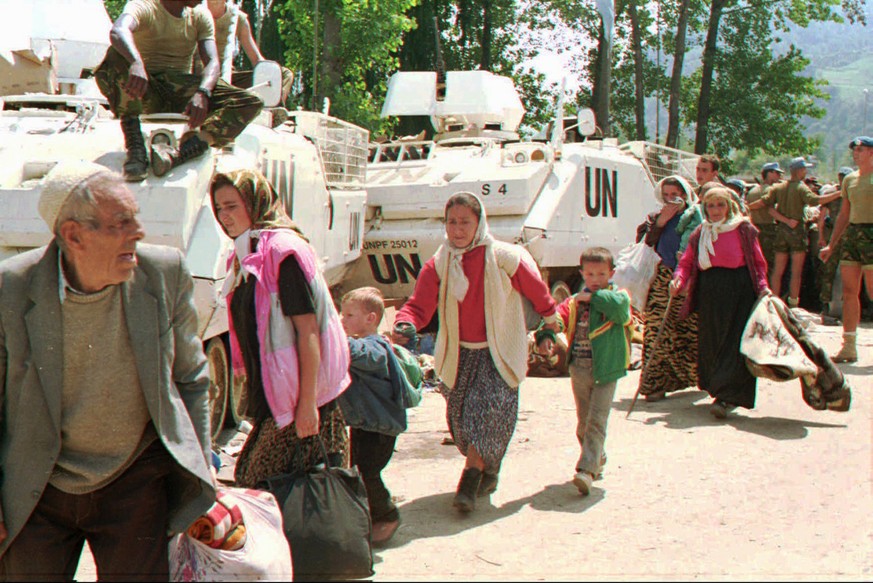 Bosnische Flüchtlinge verlassen Srebrenica 1995 neben Panzerfahrzeugen der Vereinten Nationen. &nbsp;