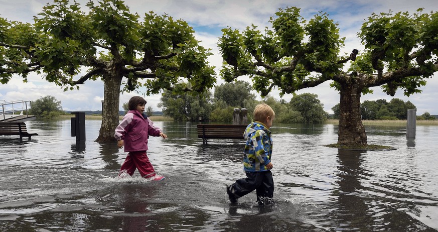 Zwei Kinder gehen am 19. Juni durch das Hochwasser beim Hafen in Gottlieben (TG).