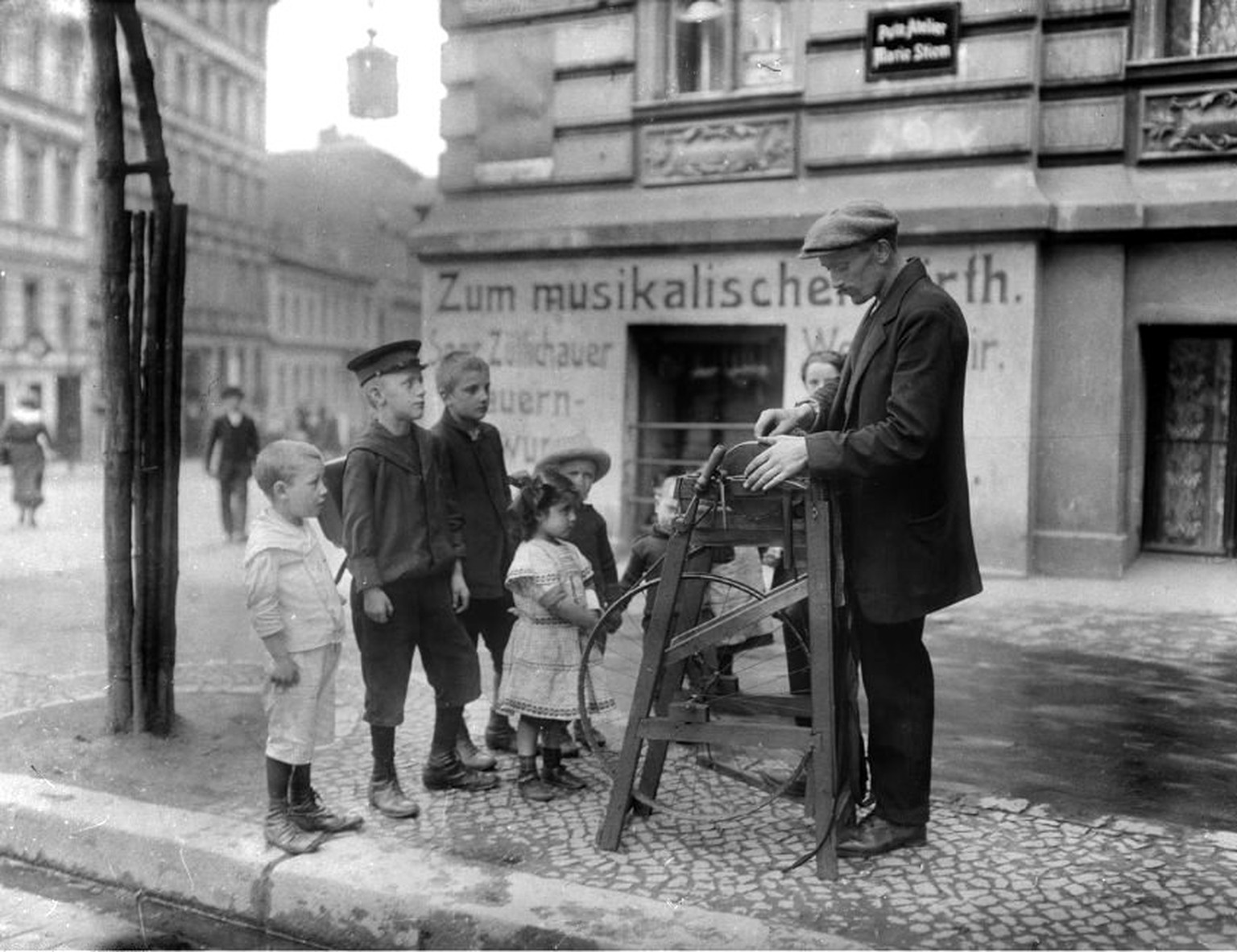 Ein Berliner Scherenschleifer, bewundert von Kindern, 1904.