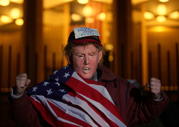 A man wearing a mask depicting U.S. President-Elect Donald Trump protests during a demonstration against climate change outside of the U.S. Embassy in London, Britain, 18 November, 2016. REUTERS/Hanna ...