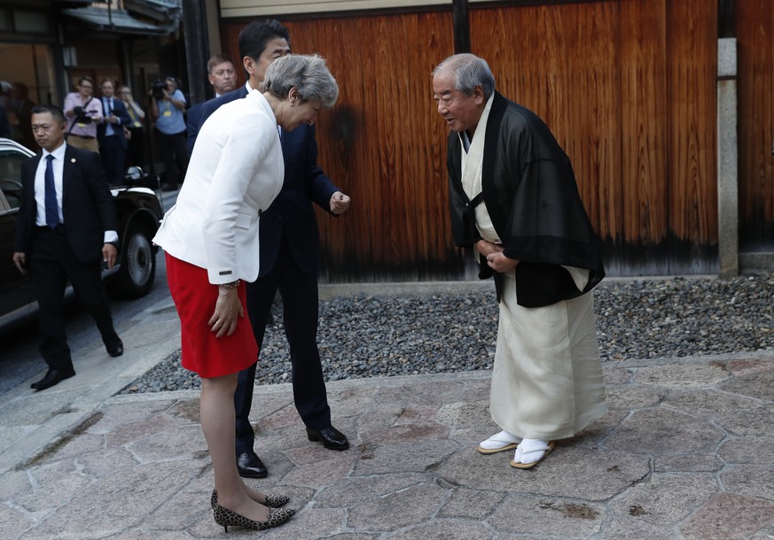 Britain&#039;s Prime Minister Theresa May, left, flanked by Japan&#039;s Prime Minister Shinzo Abe (behind May) is welcomed by Master of Tea Ceremony Sen Sosa, right, upon her arrival for a tea ceremo ...