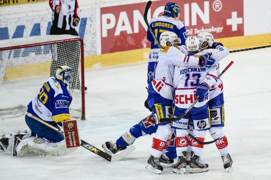 Die Klotener Romano Lemm, Simon Bodenmann und Denis Hollenstein, von links, jubeln nach Bodenmann&#039;s Tor zum 0:1 gegen den Davoser Torhueter Leonardo Genoni, links, beim Eishockeyspiel der Nationa ...