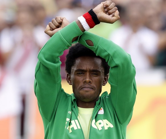 EXPLAINS SIGNIFICANCE OF GESTURE, ADDS UPDATE -Silver medalist Feyisa Lilesa, of Ethiopia, acknowledges applause during an award ceremony as he crosses his wrists in an attempt to draw global attentio ...