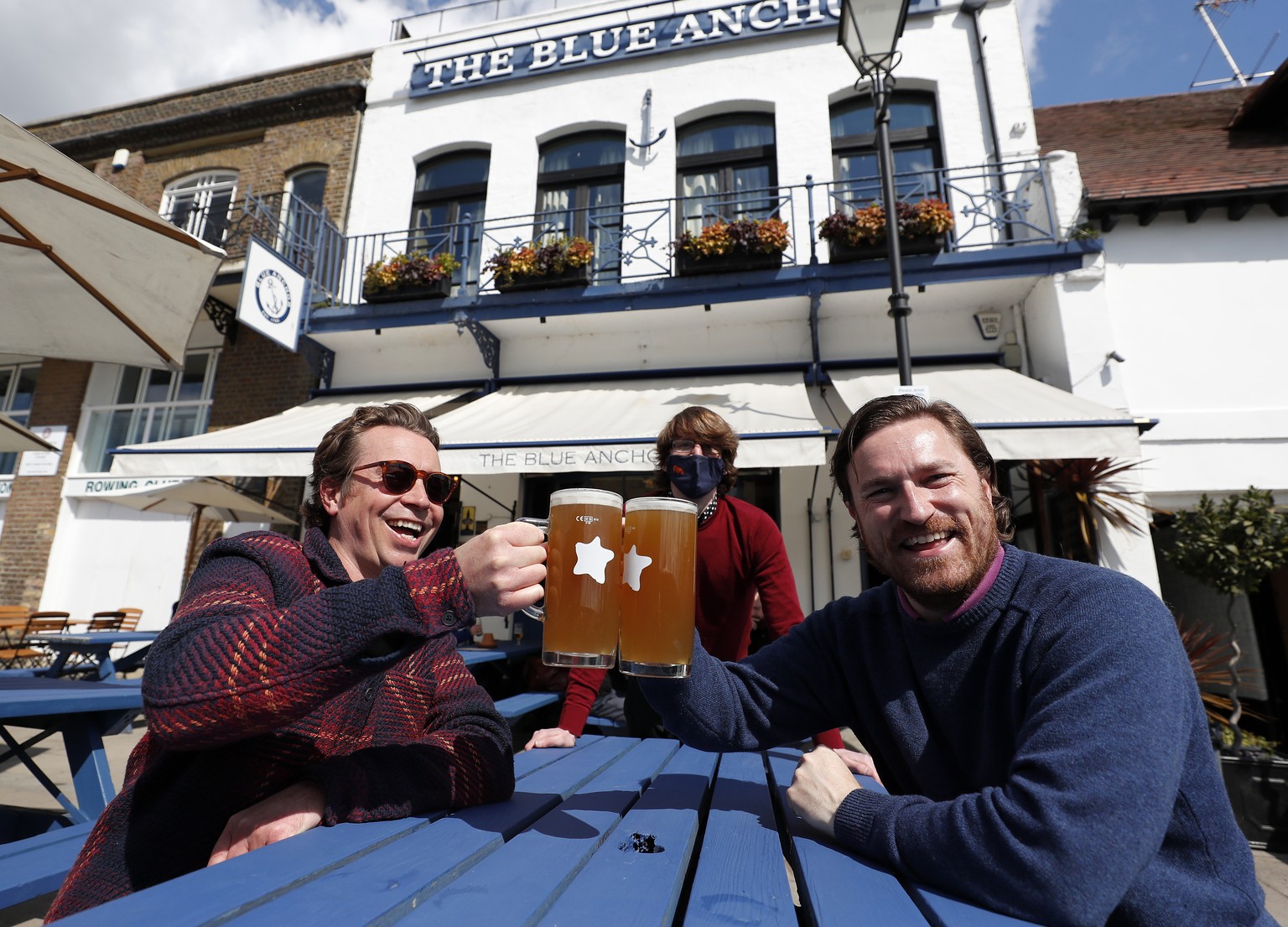 Matt and Matt enjoy their first beer outside the Blue Anchor pub on the embankment in Hammersmith, London, Monday, April 12, 2021. Millions of people in England will get their first chance in months f ...