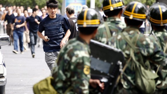 epa01787319 A men belonging to the Chinese Uyghur Moslem miniority (C) runs from Han Chinese armed with clubs and metal pipes towards a line of soldiers to get access to a Uyghur neighbourhood in Urum ...