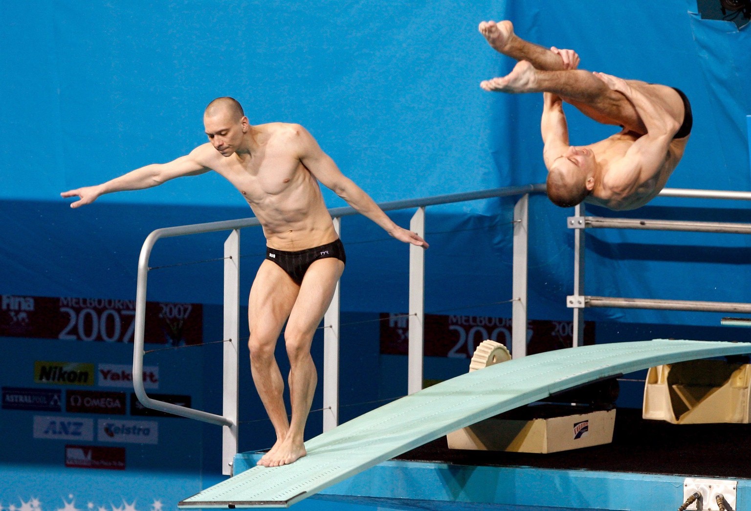 epa00960727 Russian diver Aleksander Dobroskok (L) fails to dive as his synchronised diving partner Gleb Galperin (R) dives as the Russians see their leading gold position ruined in the men's 3m ...