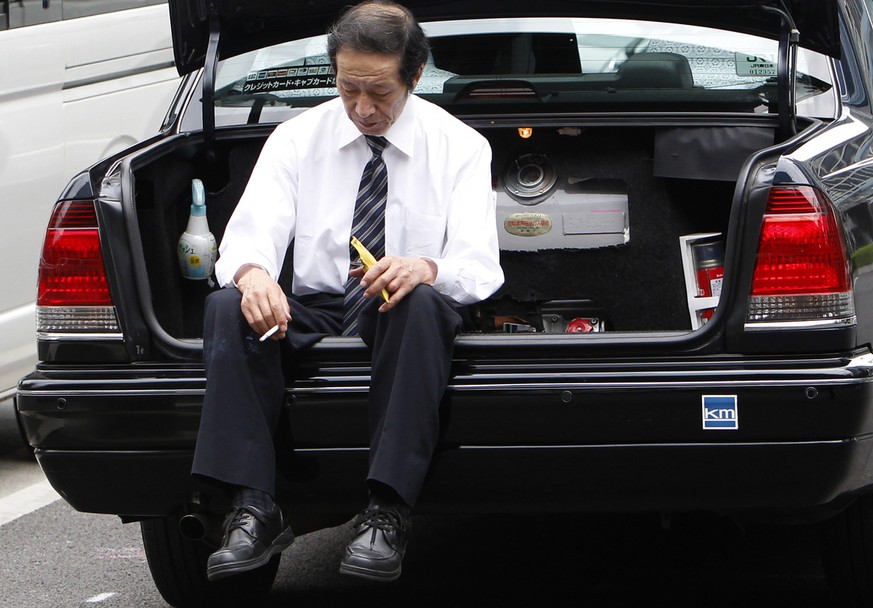 A taxi driver takes a rest, sitting on a car trunk in Tokyo, Japan, Tuesday, May 17, 2011. (AP Photo/Shizuo Kambayashi)