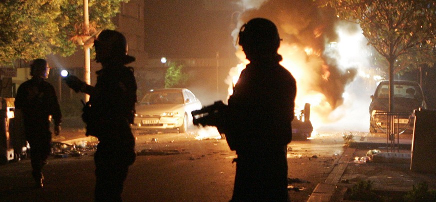 French riot police officers patrol by a burning car in Bagnolet, Paris suburban, Tuesday Aug. 11, 2009, where an 18-year old youth worked, before dying in a motorbike accident while fleeing police Sun ...