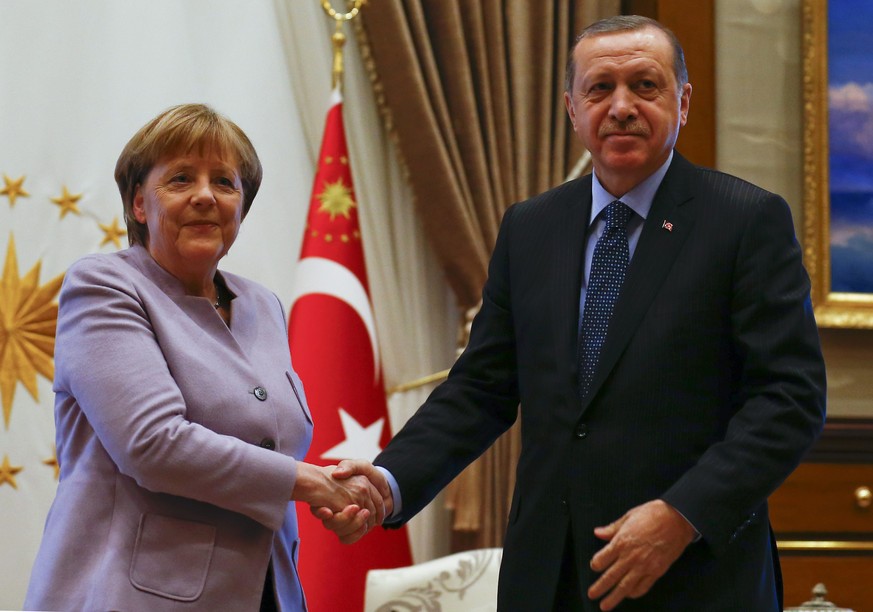 Turkish President Recep Tayyip Erdogan and German Chancellor Angela Merkel exchange a handshake at the presidential palace during the first visit since July&#039;s failed coup in Ankara, Turkey, Febru ...