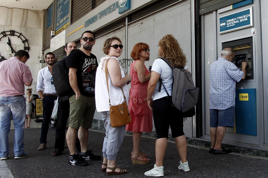 Der Alltag hat sie wieder: Griechinnen und Griechen stehen am Montag vor den Bancomaten an.